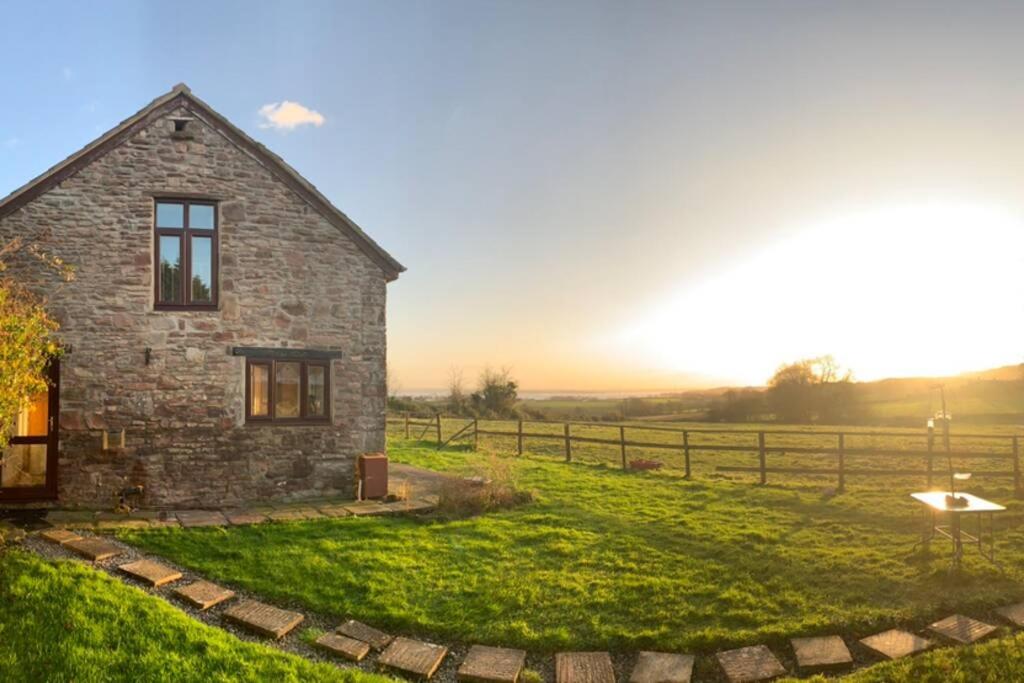 una casa de piedra en un campo con una valla en Edge Barn en Woolaston