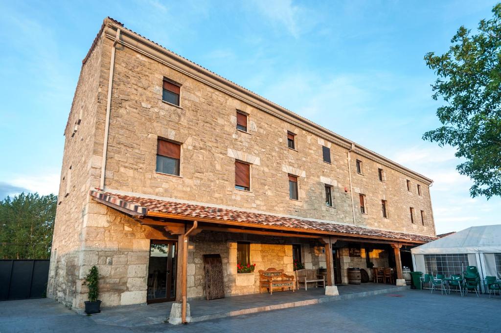 un gran edificio de ladrillo con mesas y sillas. en Albergue turístico "La Fábrica", en Tardajos