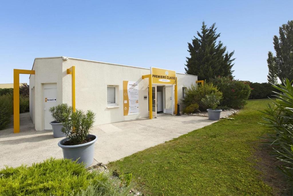 a white building with yellow poles in front of it at Premiere Classe Avignon Courtine Gare TGV in Avignon