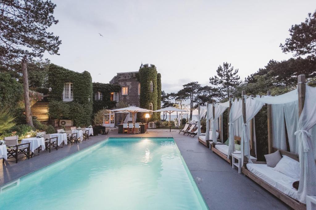 a swimming pool with tables and chairs next to a building at Domaine Saint Clair - Le Donjon in Étretat