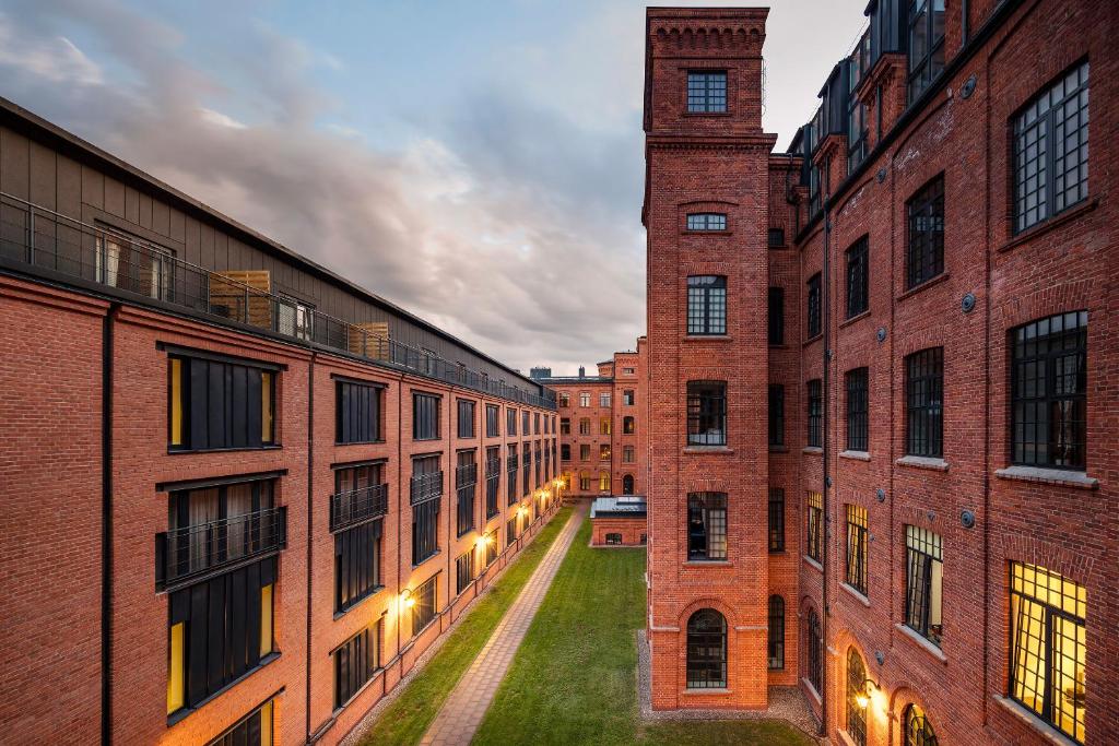 an alley between two brick buildings with a clock tower at LOFT APARTMENTS in Łódź