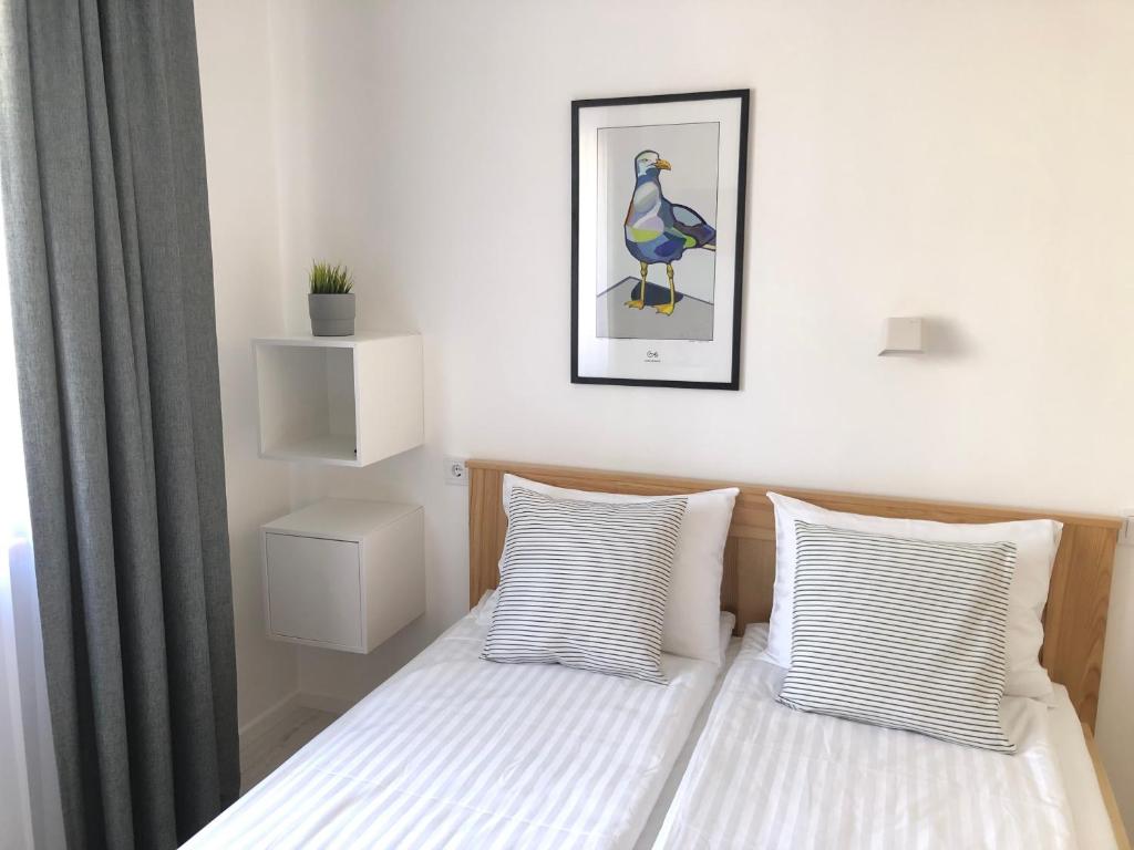 a bed with two pillows and a picture of a bird at Astos Vila in Palanga