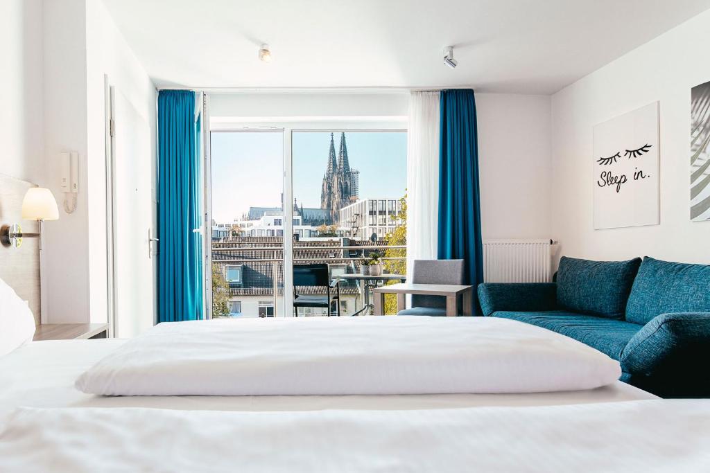 a bedroom with a bed and a blue couch at Haus am Dom - Apartments und Ferienwohnungen in Cologne