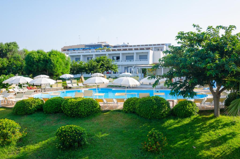 a swimming pool with umbrellas and chairs and a building at Eden Residence Club in Torre Ovo