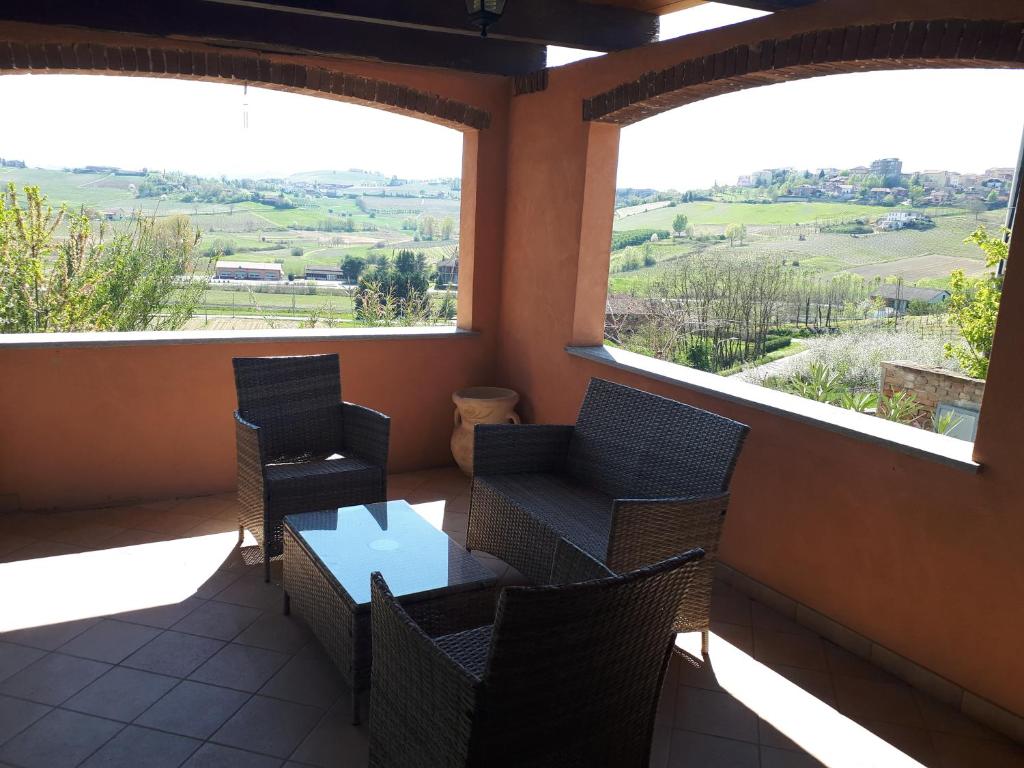 balcón con sillas, mesa y 2 ventanas en Holydays Home LITTLE FROG en Agliano Terme