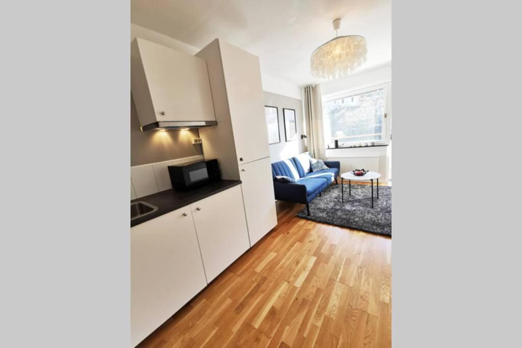 a kitchen with white cabinets and a living room at Stilren studiolägenhet på 20 kvm nära havet och centrum! Stationsterrassen 7 in Båstad