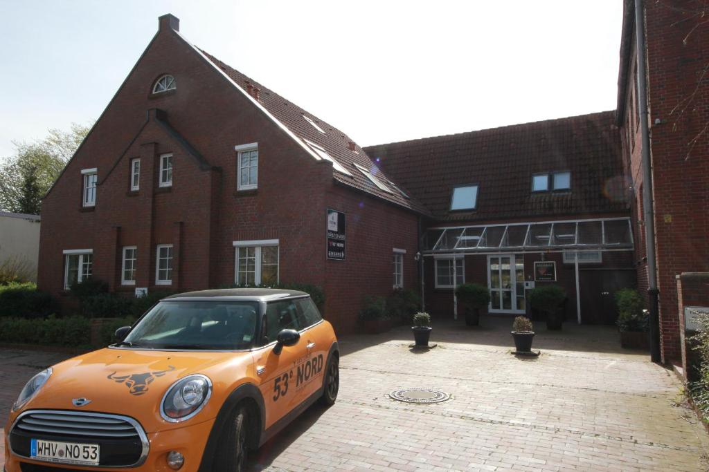 un coche naranja estacionado frente a un edificio de ladrillo en Gästehaus 53 Nord, en Wilhelmshaven