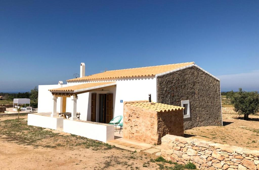 una pequeña casa blanca con una pared de piedra en Can Vicent Yern, en Sant Francesc Xavier