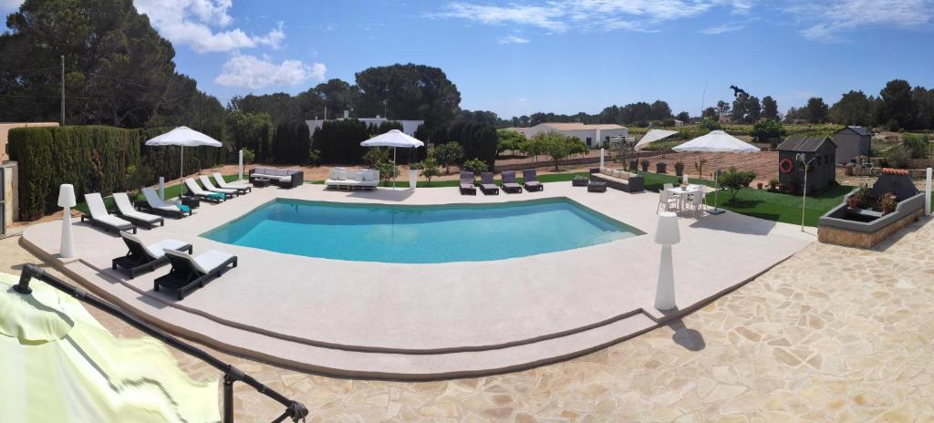 a swimming pool with chairs and a hammock around it at MAR Y MONTAÑA FORMENTERA in Sant Francesc Xavier