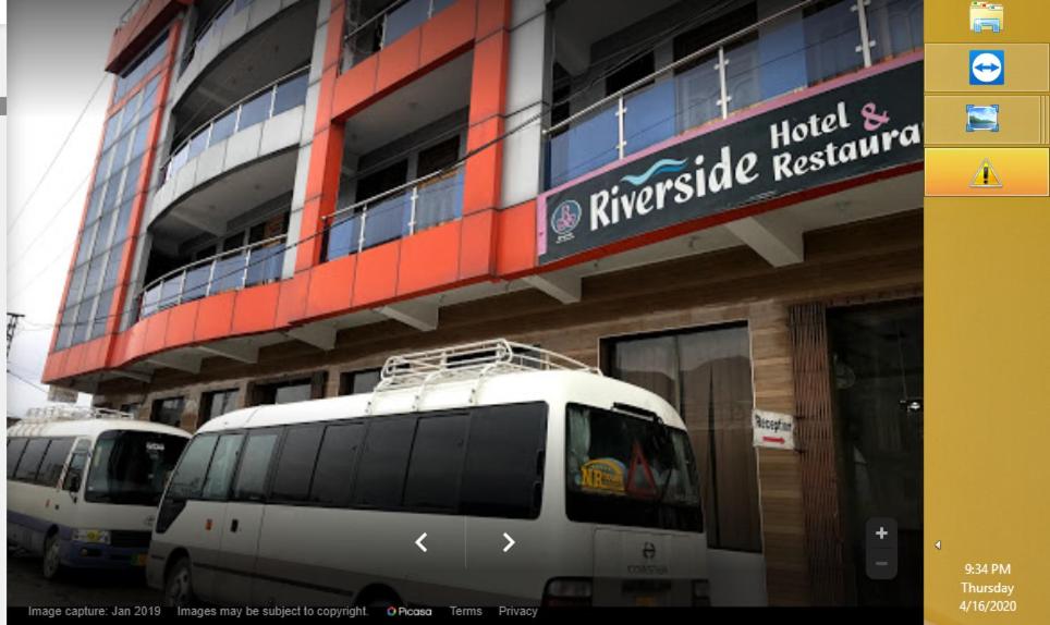 Mām Derai的住宿－Riverside Hotel，停在大楼前的两辆货车