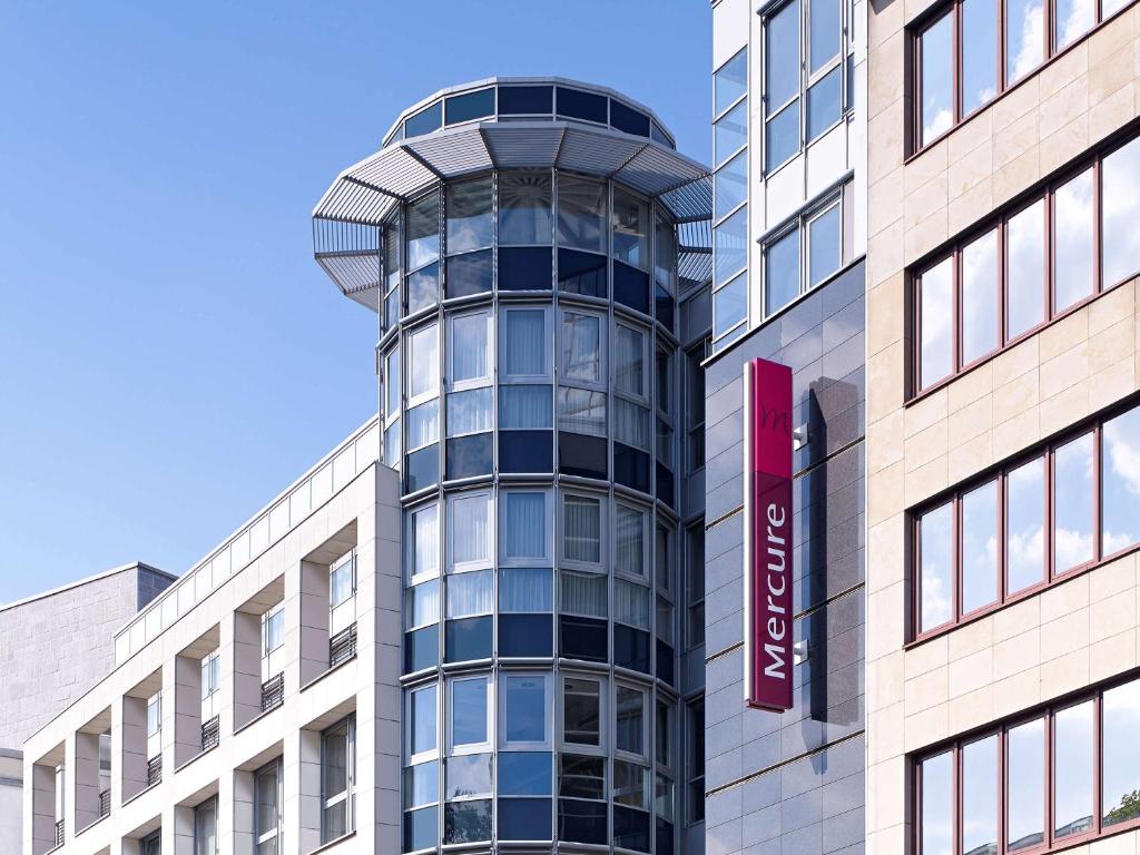 ein hohes Glasgebäude mit einem roten Schild darauf in der Unterkunft Mercure Hotel Dortmund City in Dortmund