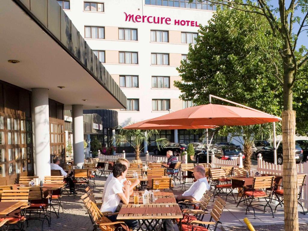 un grupo de personas sentadas en mesas fuera de un hotel en Mercure Hotel am Messeplatz Offenburg en Offenburg