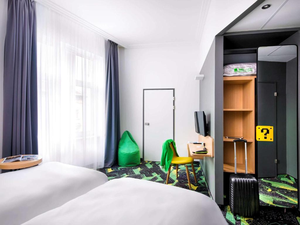 a hotel room with two beds and a chair at Ibis Styles Budapest Center in Budapest
