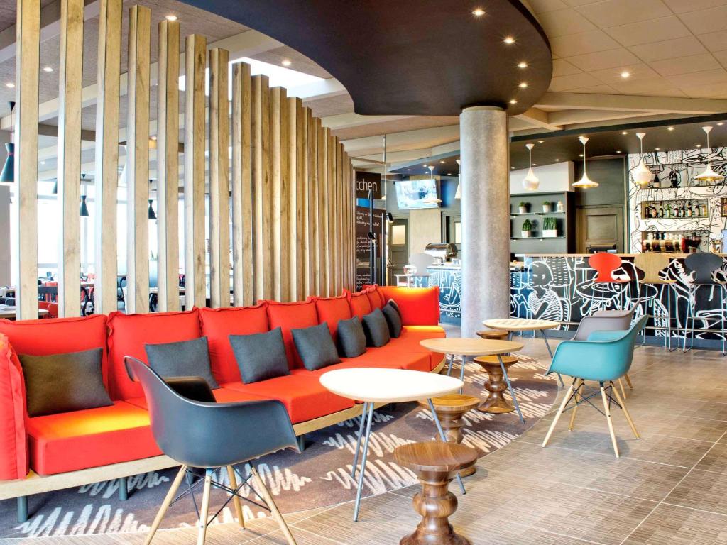 a lobby with a red couch and tables and chairs at Ibis Warszawa Ostrobramska in Warsaw