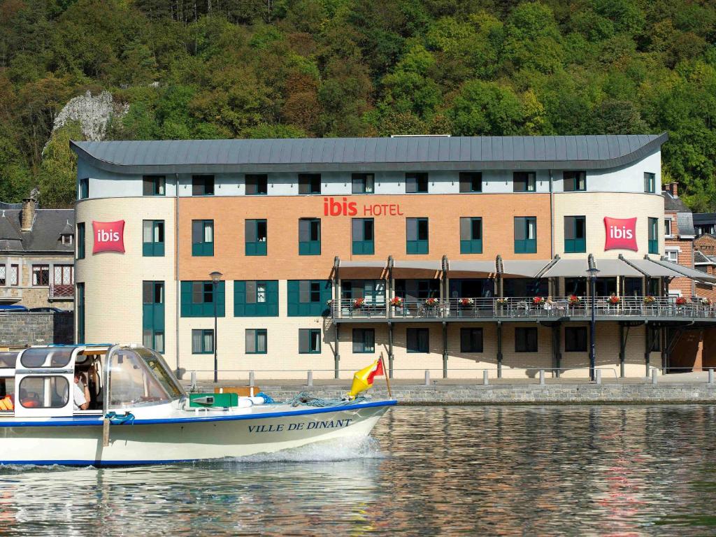 a boat in the water near a building at ibis Dinant Centre in Dinant
