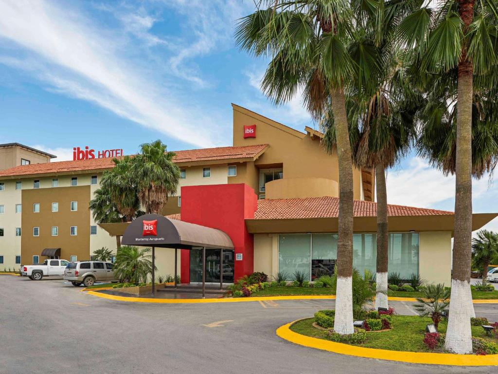 un hôtel avec des palmiers en face d'un parking dans l'établissement Ibis Monterrey Aeropuerto, à Monterrey