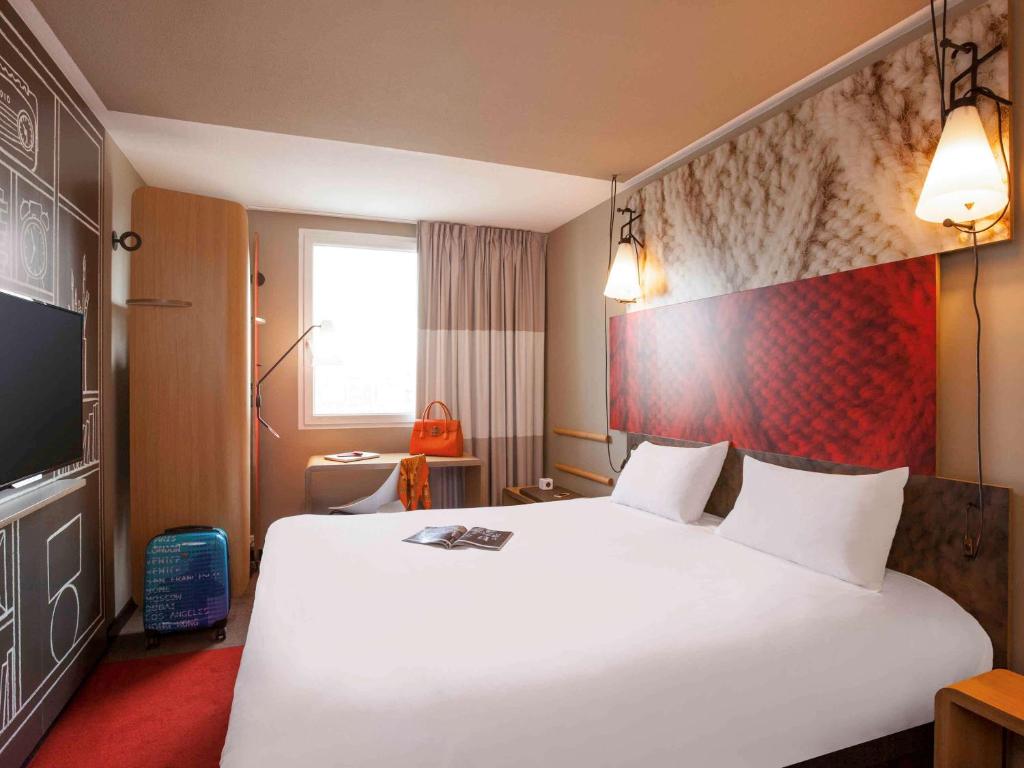 una habitación de hotel con una gran cama blanca y una ventana en ibis Paris Porte de Clichy Centre, en Clichy