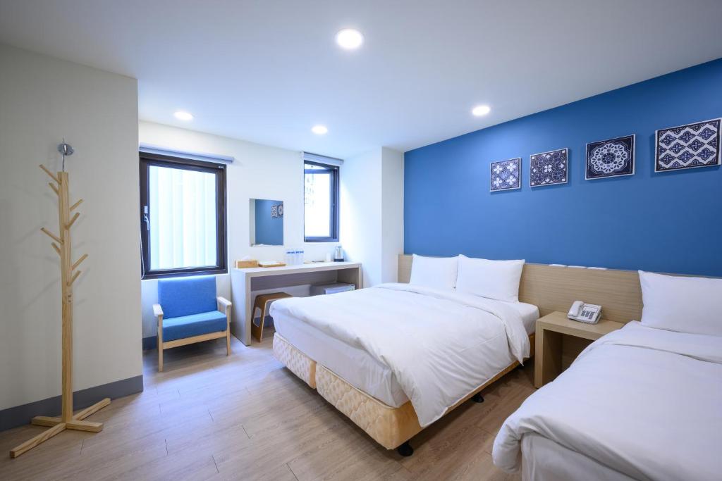 1 dormitorio con 2 camas y pared azul en P Inn en Tainan