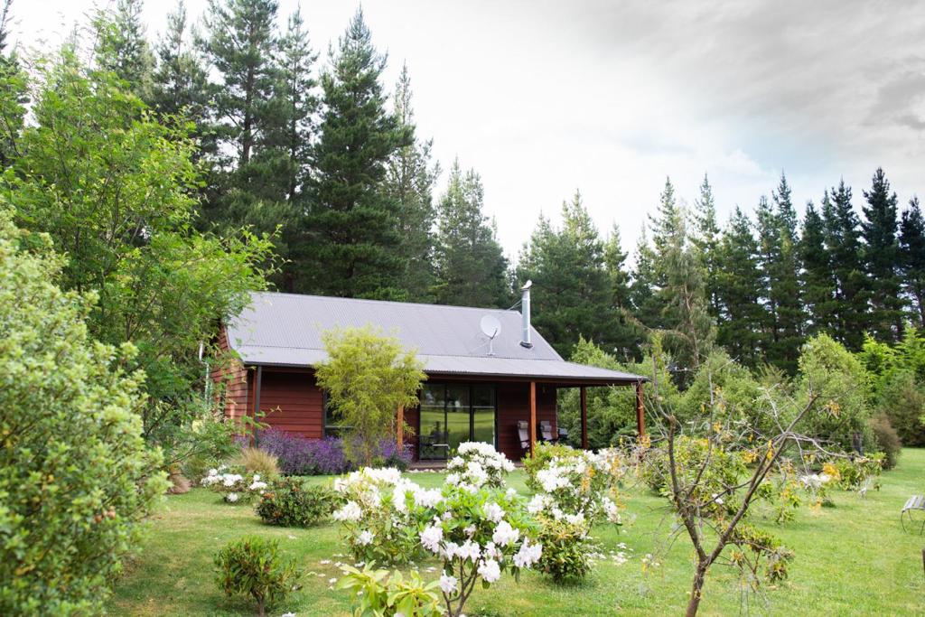 a house in the middle of a yard with trees at Woodbank Park Cottages in Hanmer Springs