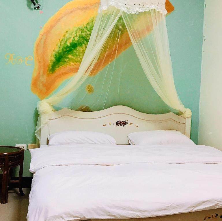 a bedroom with a bed with a painting on the wall at 花園夜市易民宿 in Tainan