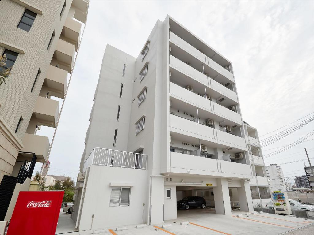 duży biały apartamentowiec z parkingiem w obiekcie M´s Stay Okinawa w mieście Chatan