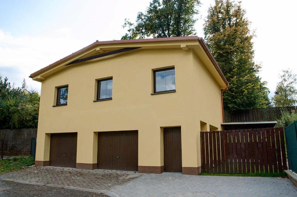 uma casa com duas portas de garagem e uma cerca em Apartmány Nad Parkem em Broumov