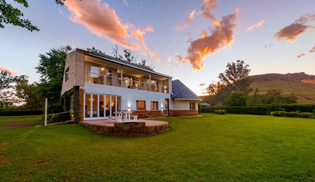 a house on a lawn with the sun setting at Woodcliffe Country House in Woodcliffs