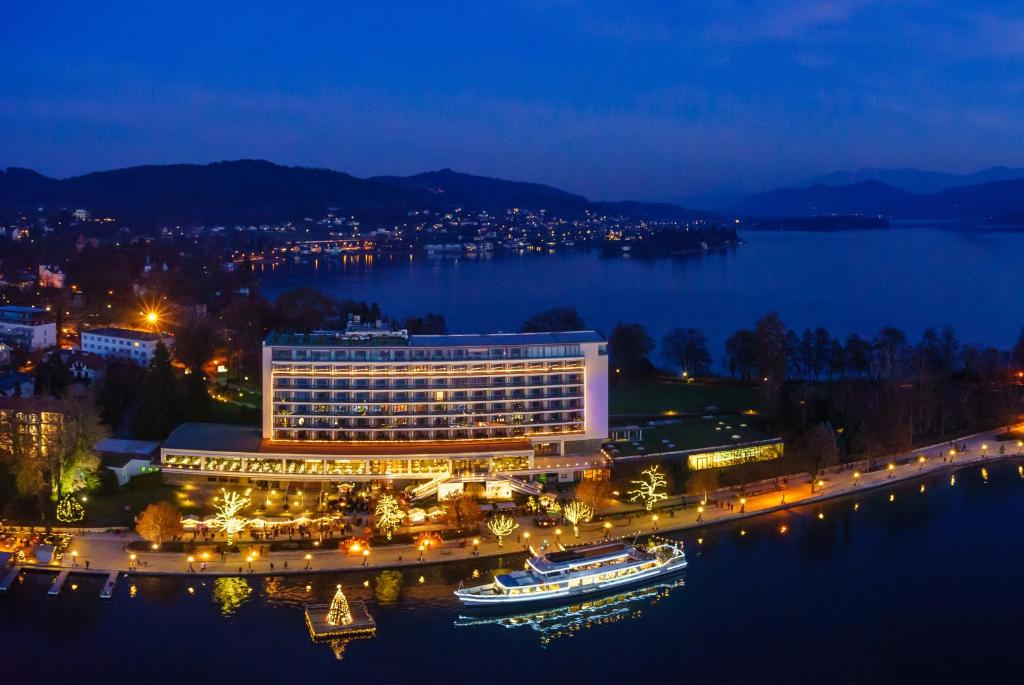 a hotel on the shore of a lake at night at Parkhotel Pörtschach - Das Hotelresort mit Insellage am Wörthersee in Pörtschach am Wörthersee