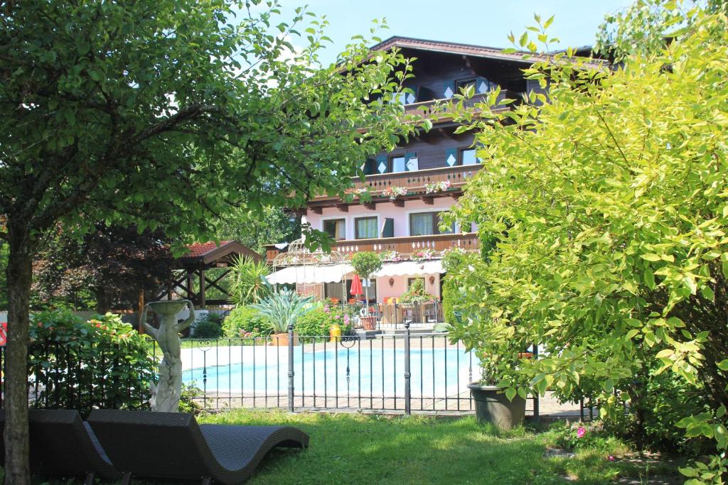 een gebouw achter enkele bomen en een hek bij Altachhof Hotel und Ferienanlage in Saalbach Hinterglemm