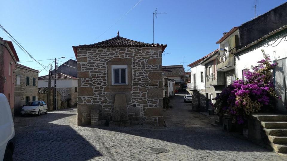 a small stone building in a street with flowers at House Diogo in Bemposta