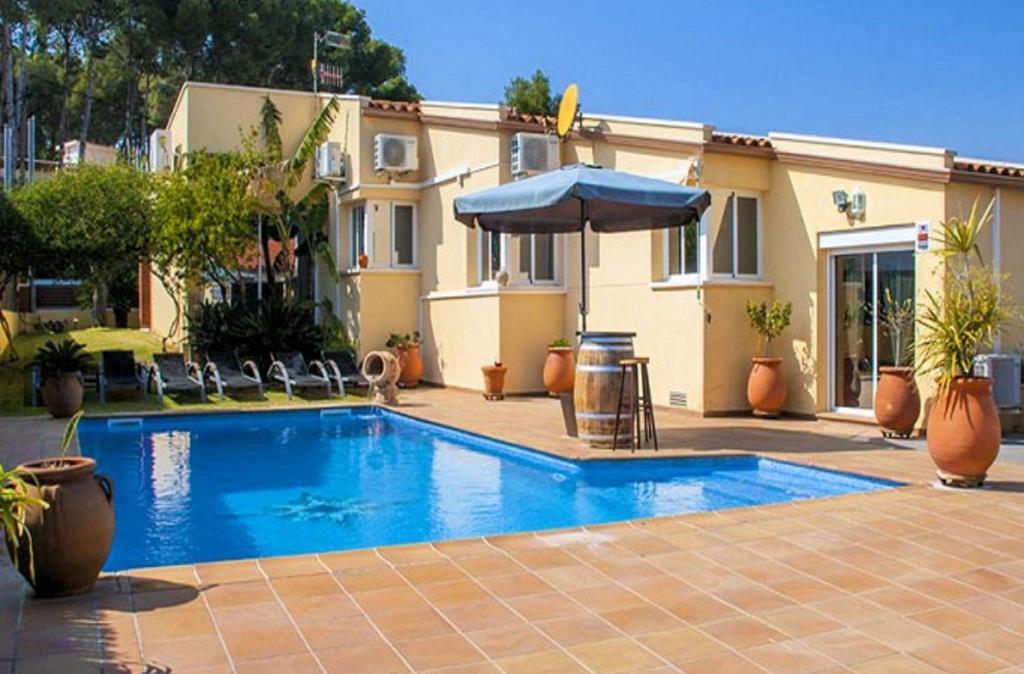 ein Swimmingpool mit Sonnenschirm und ein Haus in der Unterkunft R88 Casa Alegre in Segur de Calafell