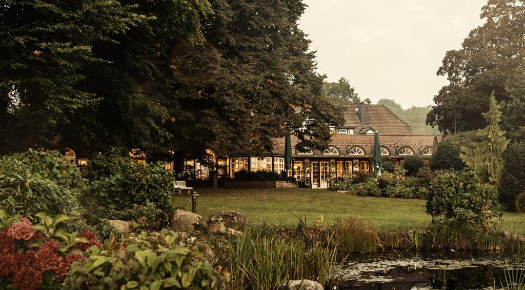 una casa con un estanque frente a un jardín en Romantik Hotel Bösehof, en Bad Bederkesa