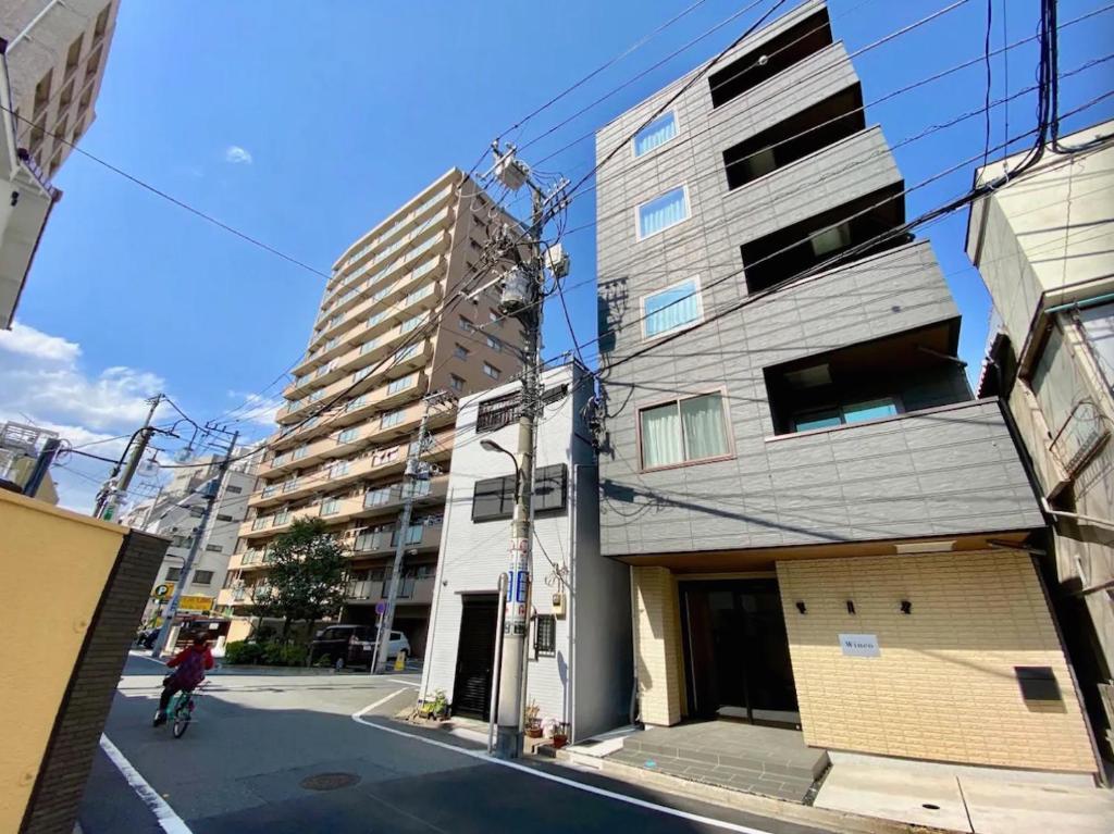 東京的住宿－Sugamo Winco Residence，骑着自行车沿着建筑旁边的街道骑行的人