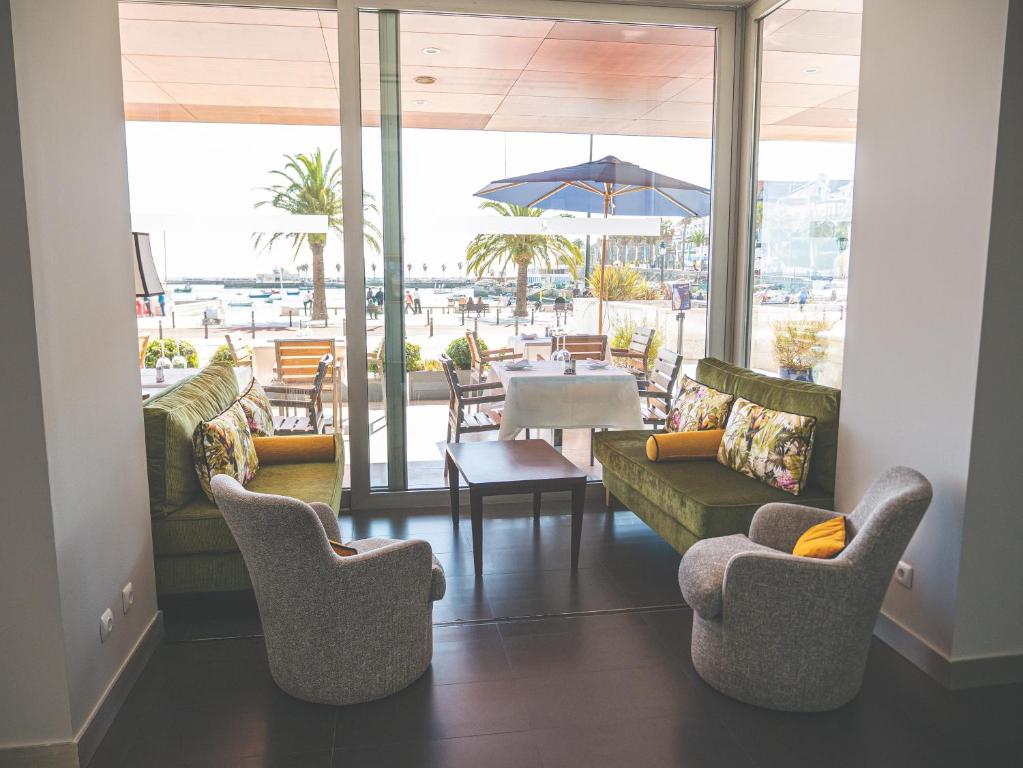 a living room with chairs and a table with an umbrella at Hotel Baia in Cascais