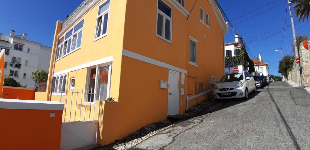 un bâtiment jaune avec une voiture garée à côté dans l'établissement Chalet Ludovina, à Estoril
