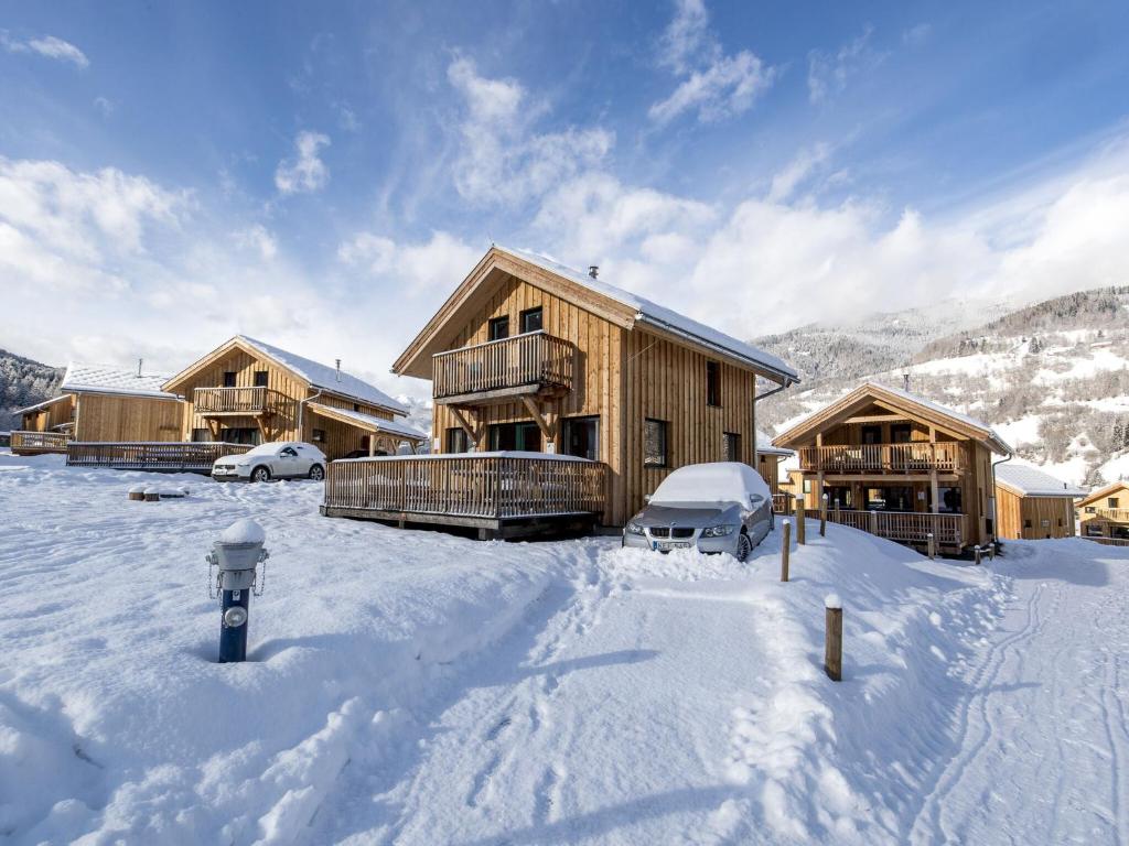 a group of wooden buildings in the snow at Modern Wooden Chalet in Sankt Georgen ob Murau with Jacuzzi in Sankt Lorenzen ob Murau