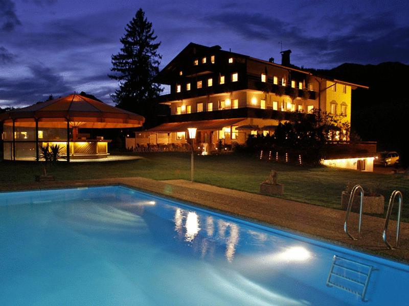 a swimming pool in front of a house at night at Hotel Hagerhof in Thiersee