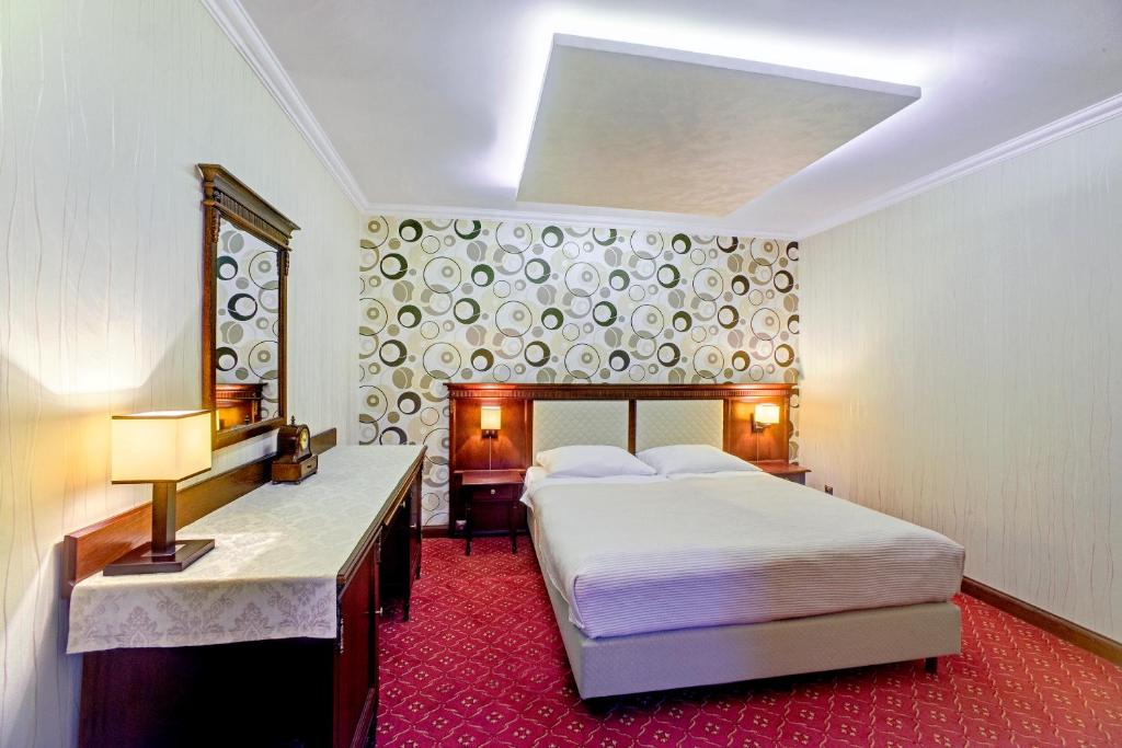TuczempyにあるHotel Zajazd Polonezの大きなベッドとデスクが備わるホテルルームです。