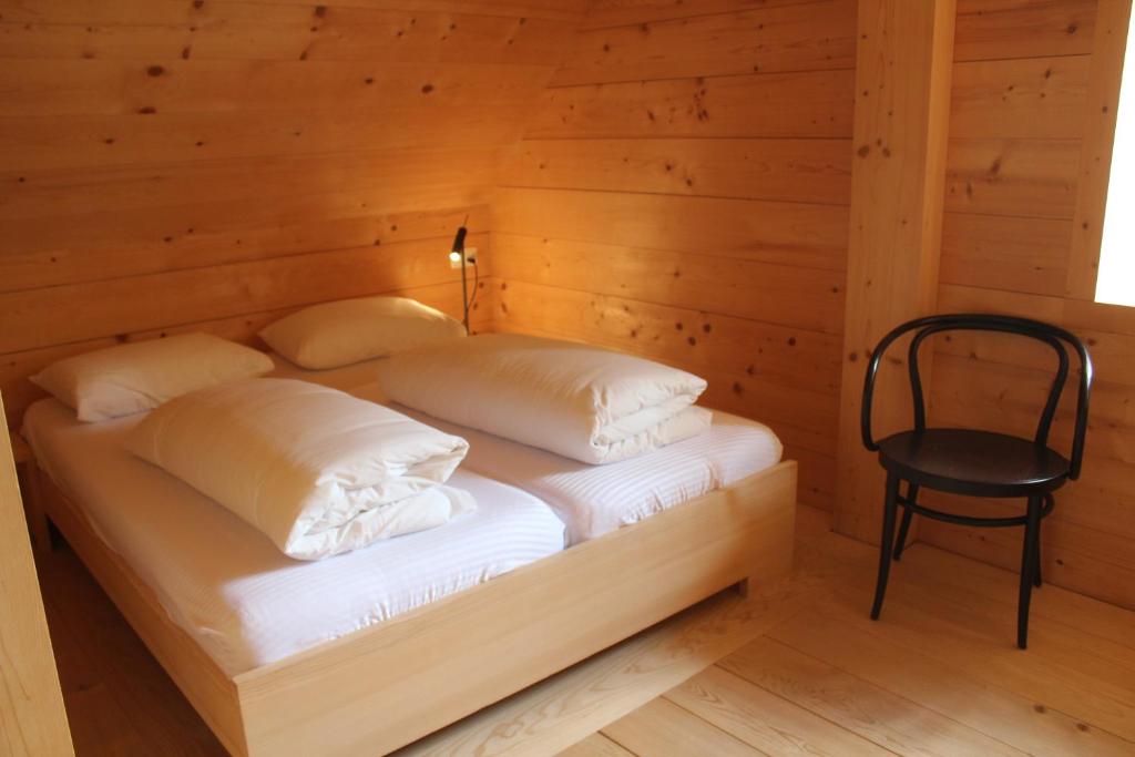 a bed in a wooden room with a chair at Ospizio San Gottardo in Airolo