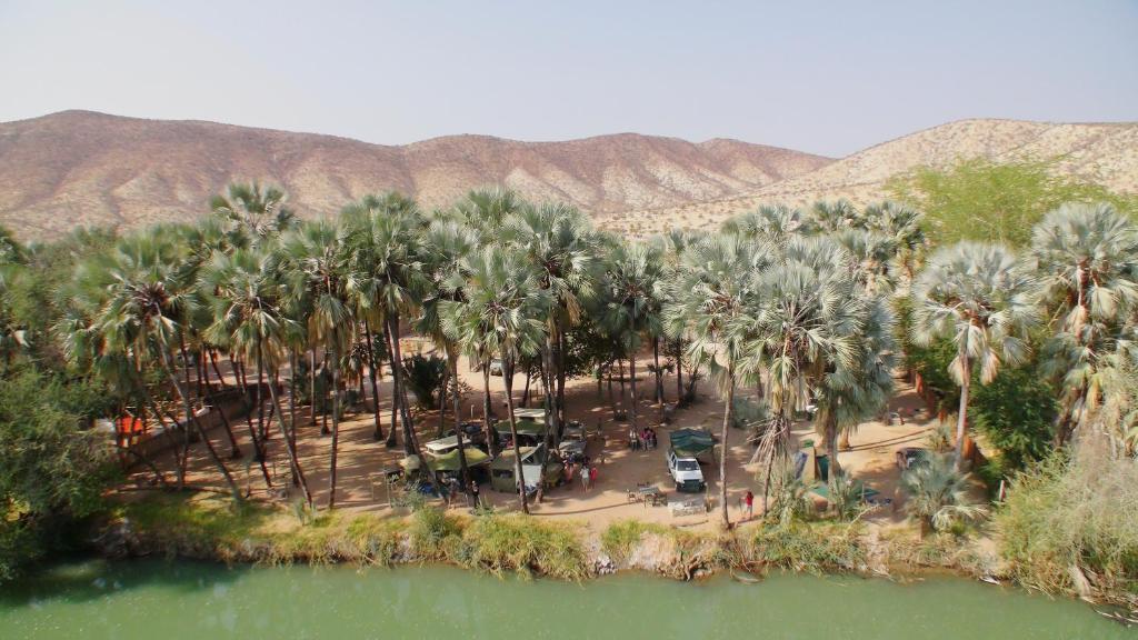 una vista aérea de un complejo con palmeras y agua en Omarunga Epupa-Falls Campsite, en Epupa