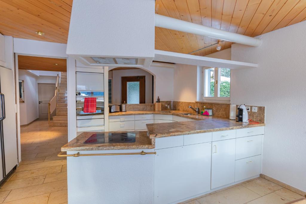 グリンデルワルトにあるChalet Weidの白いキャビネットと木製の天井が備わるキッチン