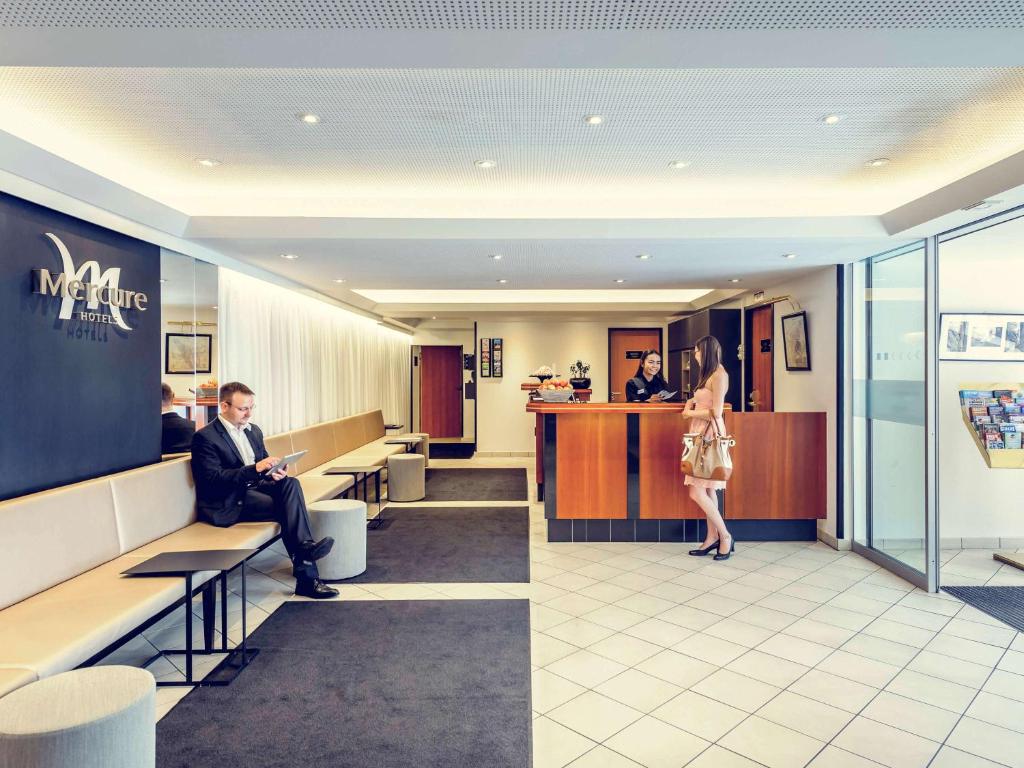 un homme assis sur un banc dans une salle d'attente dans l'établissement Mercure Hotel München Altstadt, à Munich