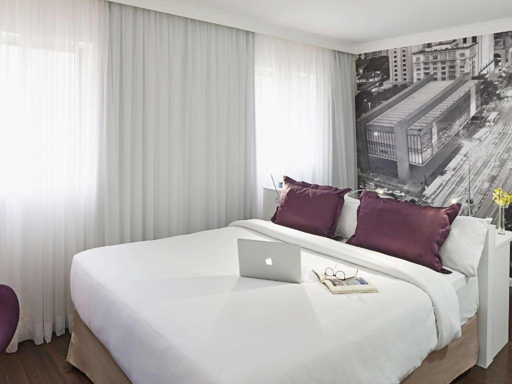 a bedroom with a large bed with a laptop on it at Mercure Sao Paulo Paulista in Sao Paulo