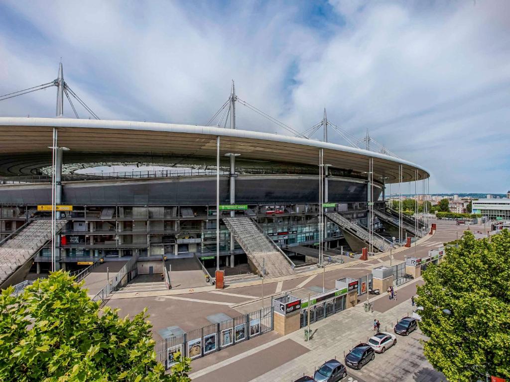 duży budynek z samochodami zaparkowanymi przed nim w obiekcie Novotel Suites Paris Stade de France w mieście Saint-Denis