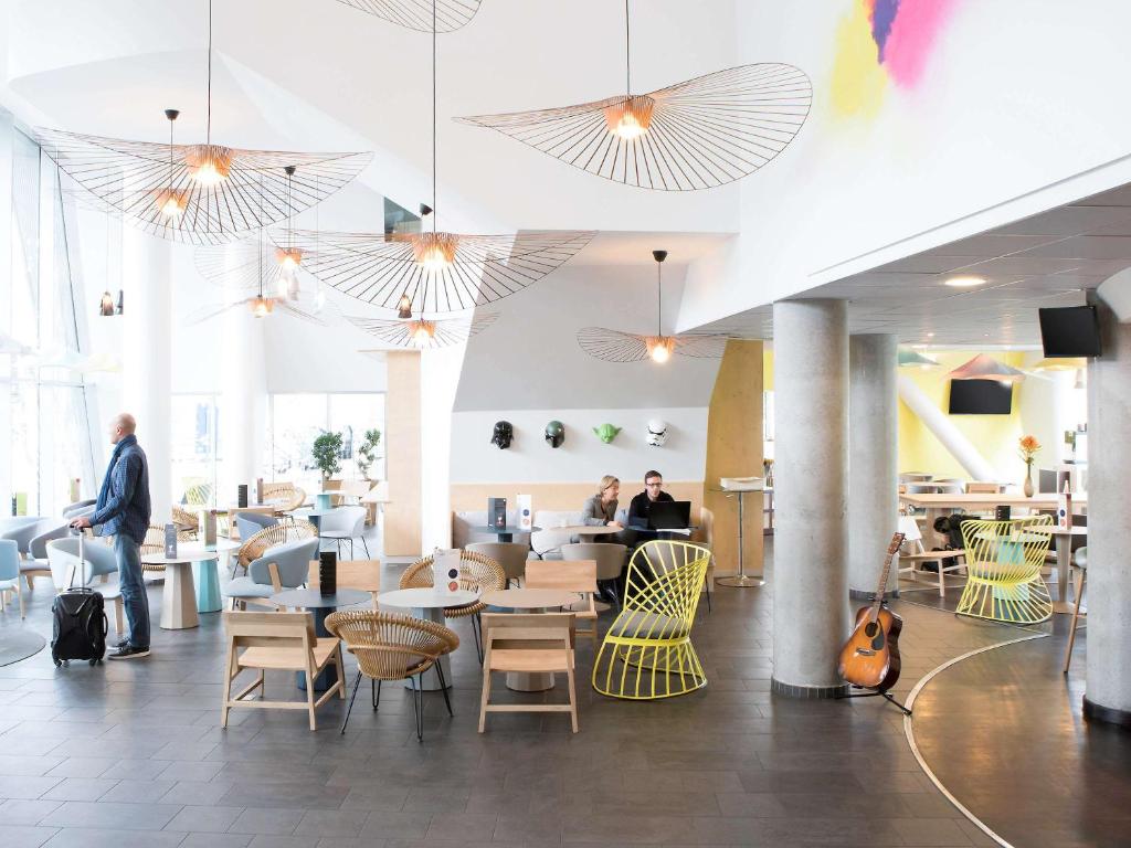 a lobby with people sitting at tables and chairs at Novotel Suites Lille Europe in Lille