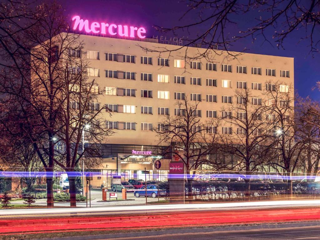 a large building with a neon sign on it at Hotel Mercure Toruń Centrum in Toruń