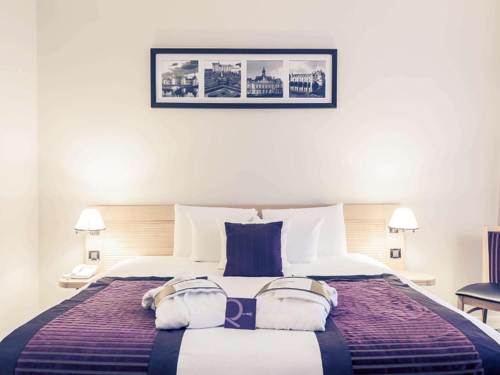 una camera da letto con un grande letto con due cuscini sopra di Mercure Tours Centre Gare et Congrès a Tours