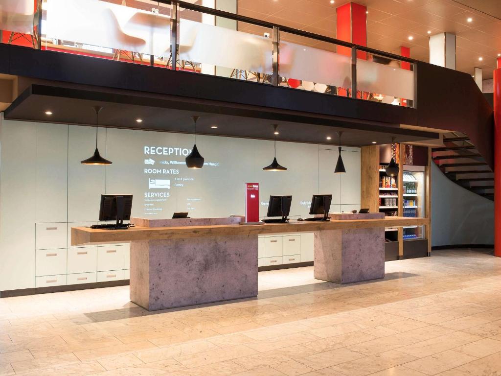 a lobby with a counter with laptops on it at Ibis Den Haag City Center in The Hague