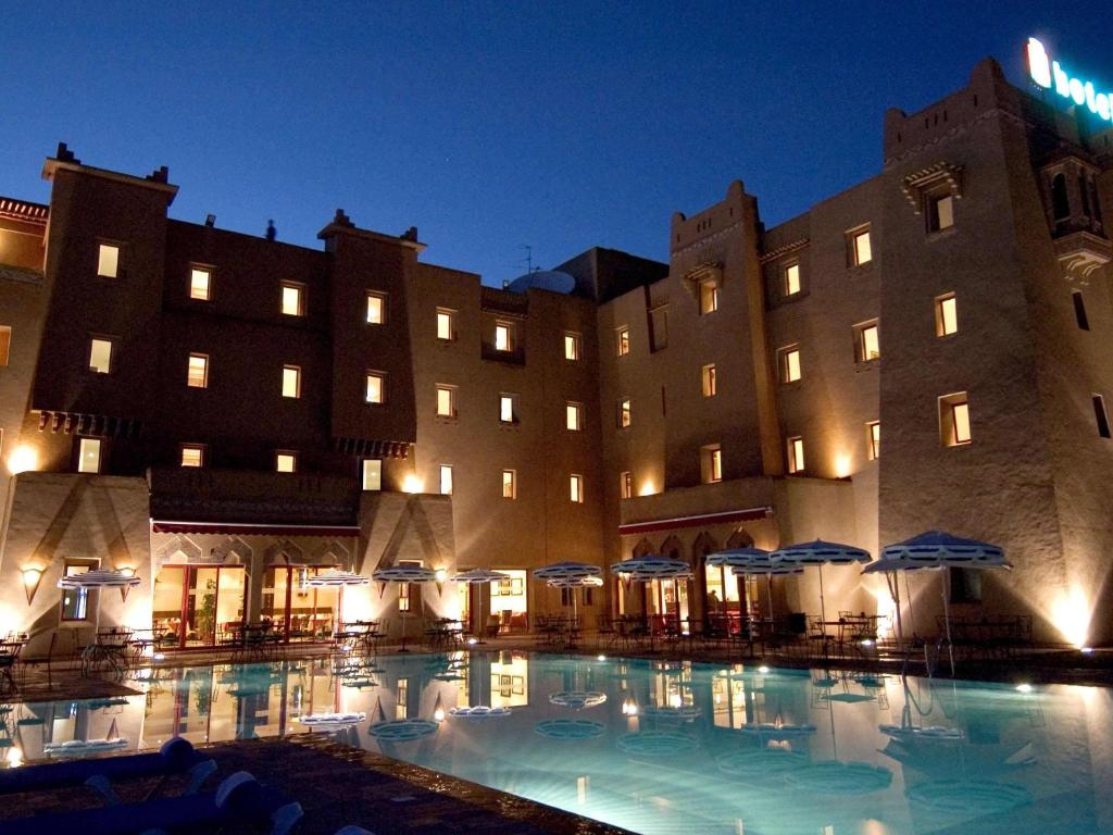 a large building with a large swimming pool at night at Ibis Ouarzazate in Ouarzazate