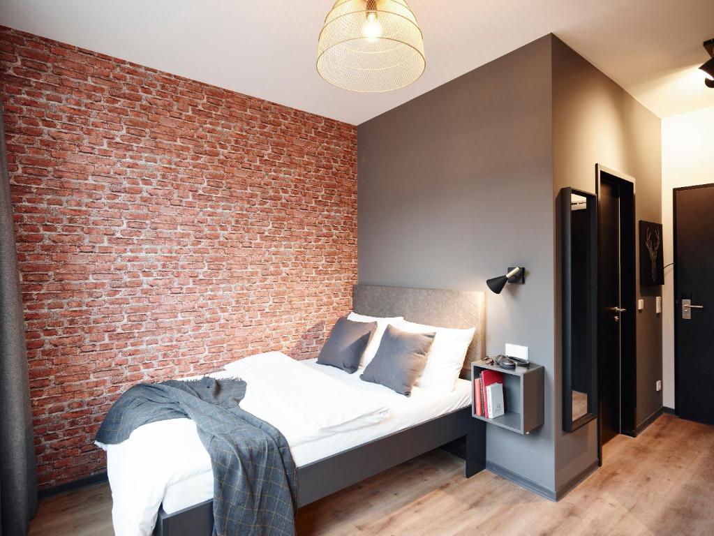 PHNX Aparthotel Hamburg في هامبورغ: غرفة نوم بحائط من الطوب وسرير